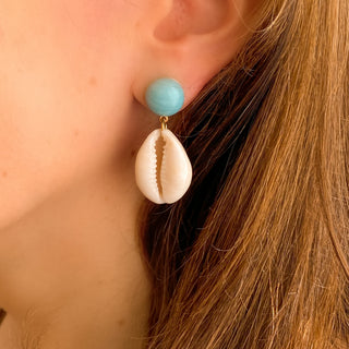 Boucles d’oreilles Océane pendantes dorées en coquillage cauri et amazonite zoom porté, montrant la longueur, la texture du coquillage et la douceur de l’amazonite, disponibles en percées ou clips. 