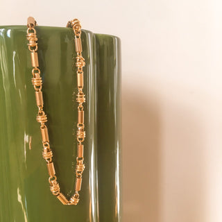 Collier Léon en chaîne dorée large, détail posé mettant en valeur les maillons et la finition dorée à l’or fin 24 carats.