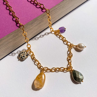Collier Nora Youm posé à plat, lumière douce, mettant en valeur les perles et pierres naturelles.