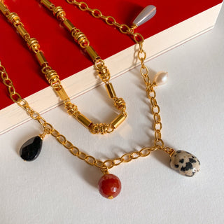 Collier en chaîne dorée large et collier avec des pierres naturelles, détail posé mettant en valeur les maillons et la finition dorée à l’or fin 24 carats.