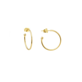 Créoles Catherine MM dorées, diamètre 2 cm, en laiton doré à l’or fin 24 carats, portées seules ou personnalisables avec des charms interchangeables en pierres et perles, packshot sur fond neutre.
