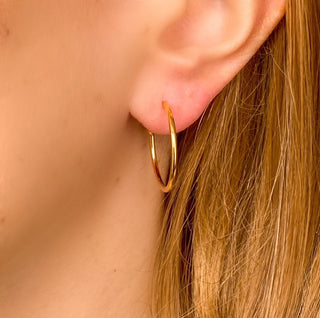 Créoles Catherine MM dorées portées, diamètre 2 cm, pouvant se porter seules ou avec des charms interchangeables en pierres ou perles naturelles.
